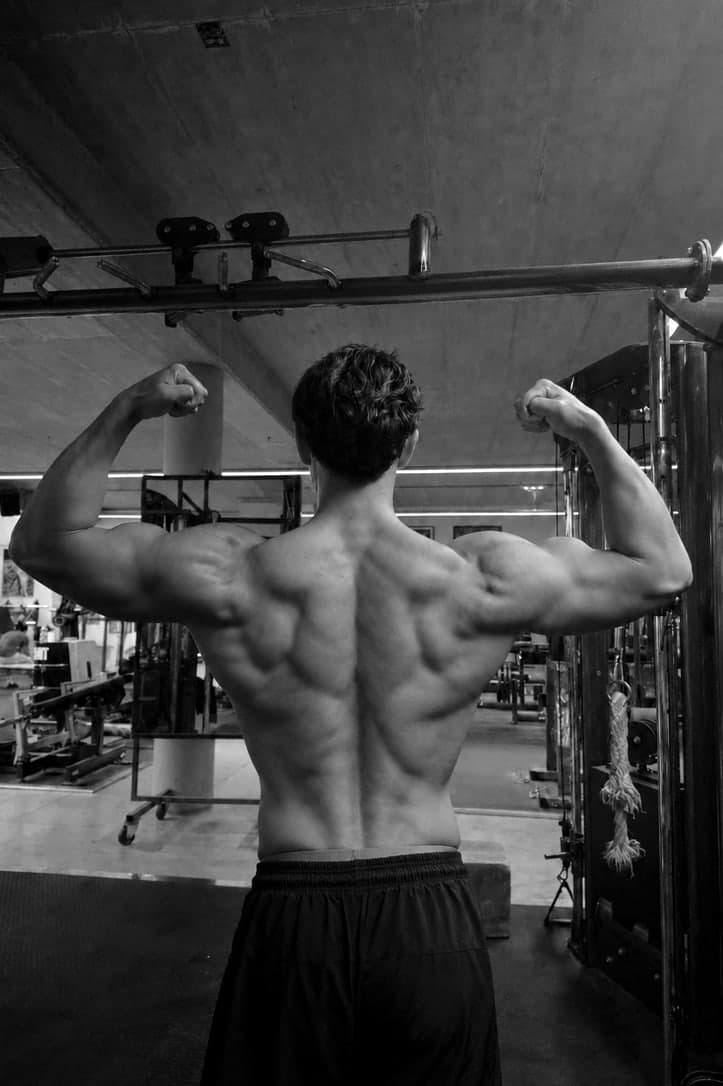 Black-and-white photo of Wilhelm Dang holding a back double-biceps pose in the gym